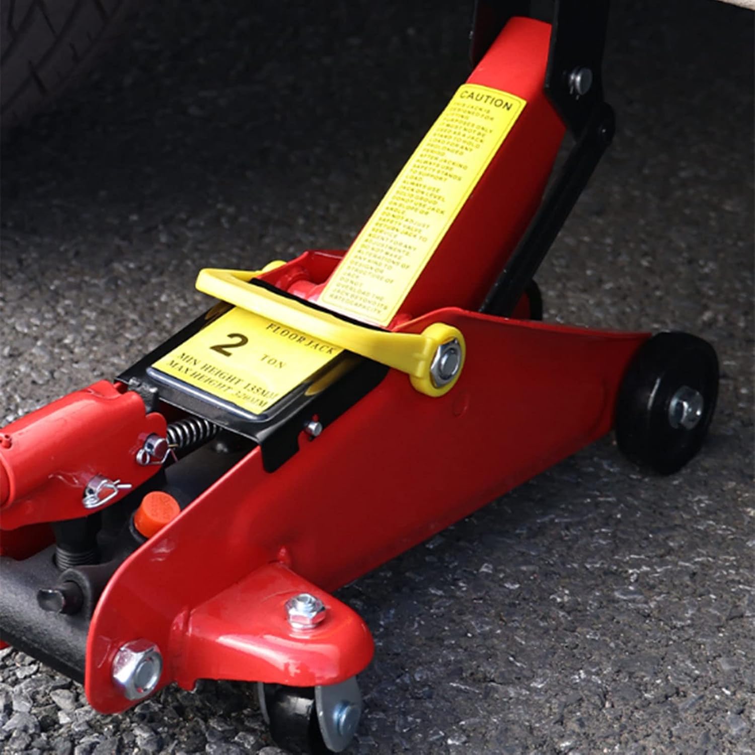 Red floor jack with a yellow label on a dark surface